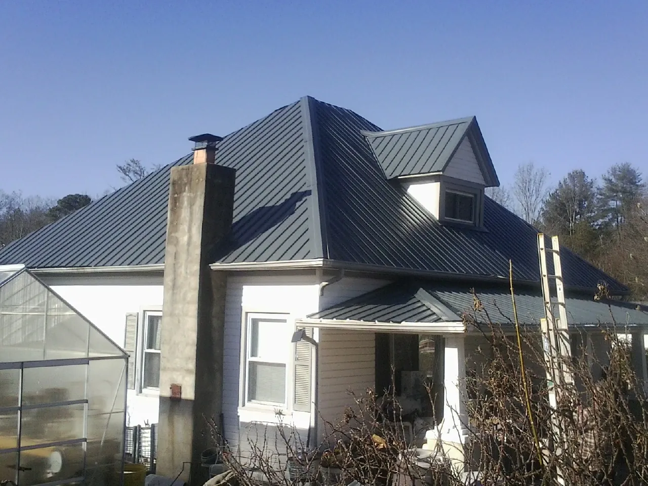 Dark blue standing seam metal roof on a white farmhouse with dormer — Slate & Tile Roof Repair by Roofing Brothers in Donaldson