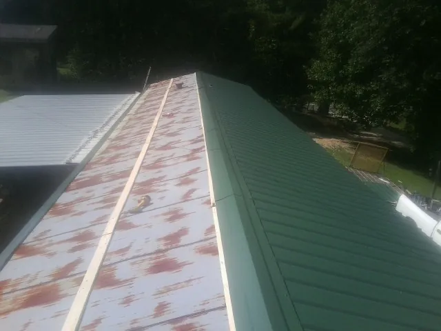 Old rusted panels beside newly installed green metal roofing — Wind Damage Roof Repair by Roofing Brothers in Donaldson