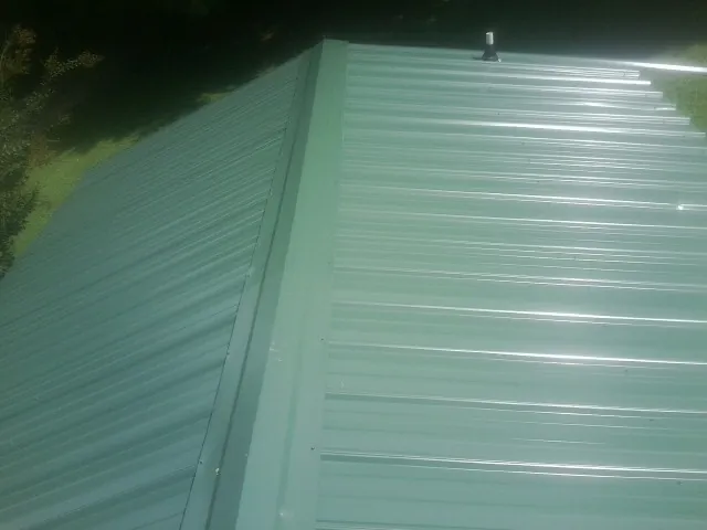 New green metal panels meeting at the ridge of a roof — Flat Roof Repair work by our crew in Donaldson