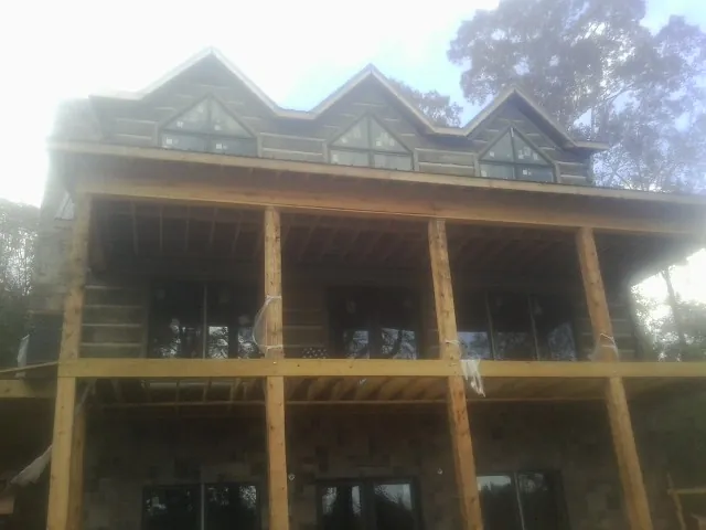 Dormers and porch framing on a large log home under construction — Roof Coating work by our crew in Donaldson