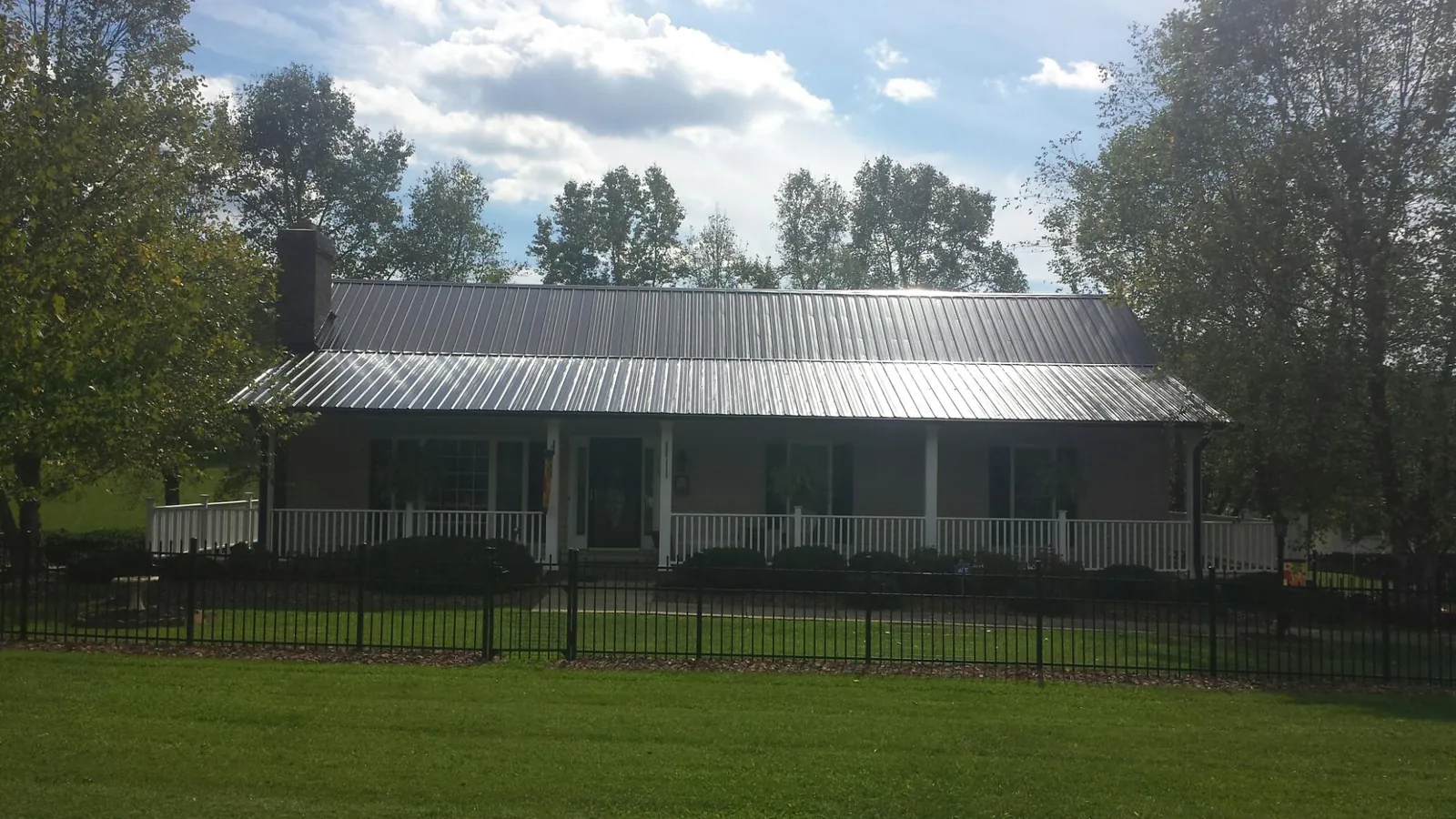 Gray metal roof on a brick ranch with a full width front porch — Gutter Guard Installation work by our crew in Donaldson