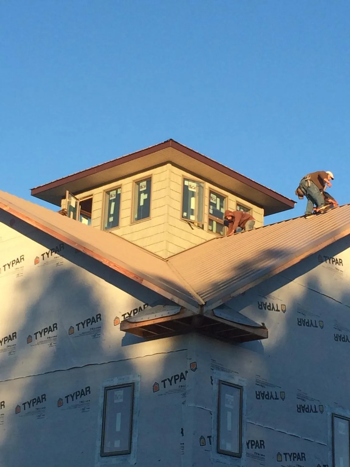 Roofers working around a rooftop cupola on a new metal roof at sunset — Roof Waterproofing in Donaldson by Roofing Brothers